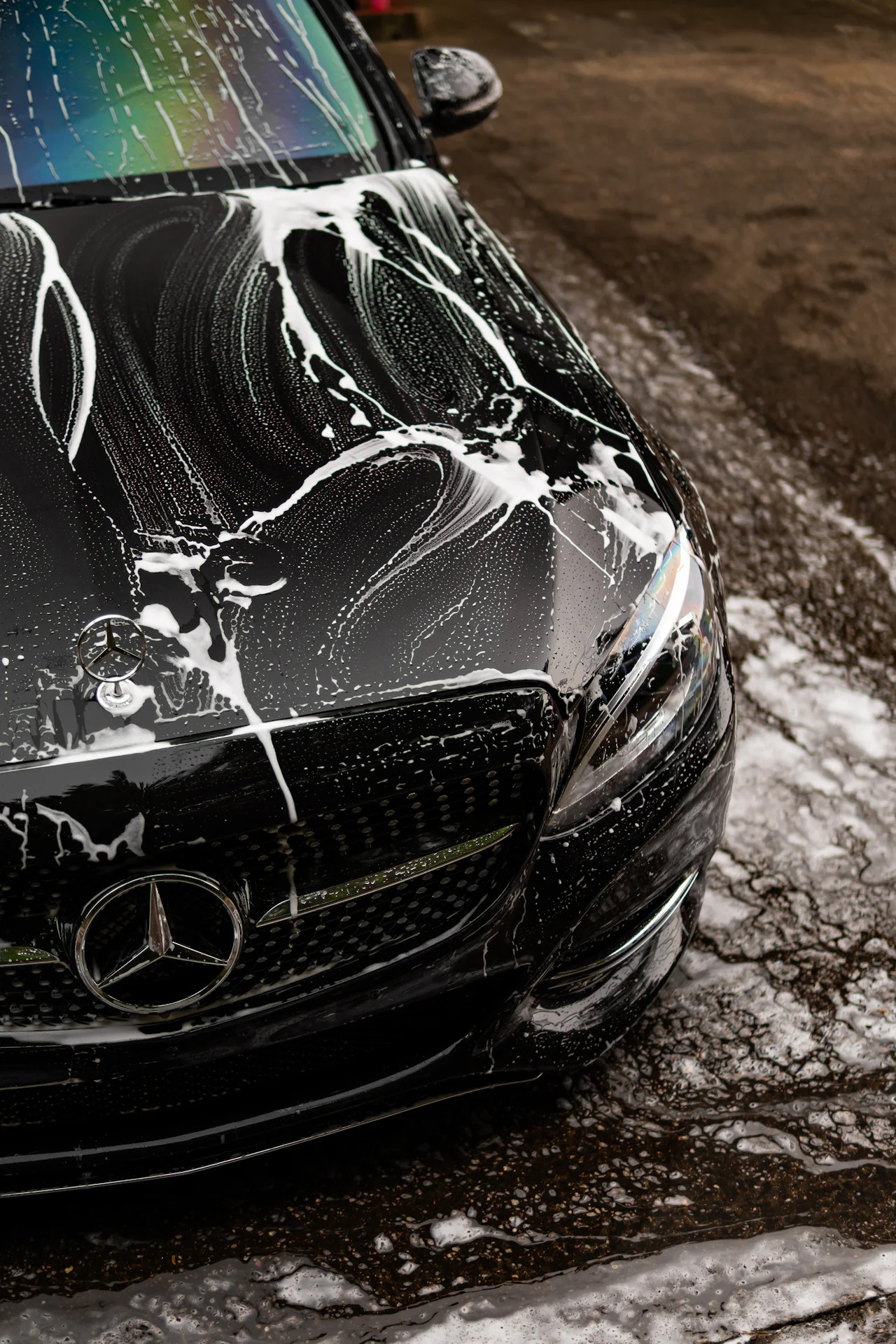Capô de carro preto coberto de espuma durante a lavagem
